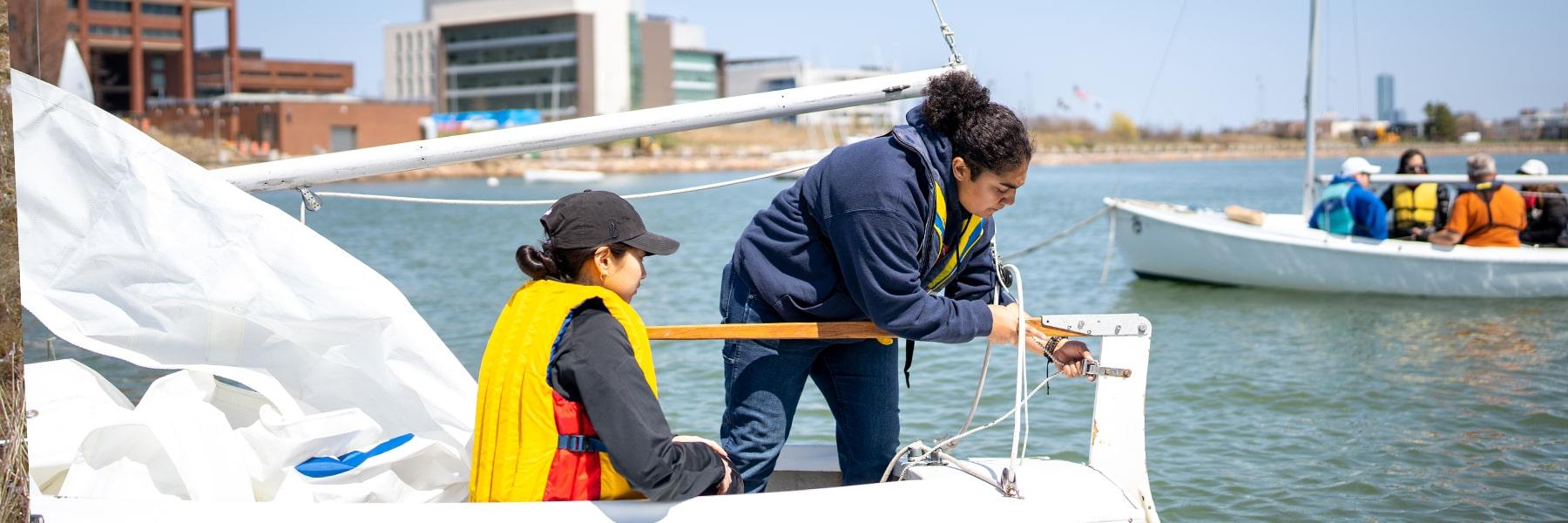两名学生在澳门新葡新京官方附近水域的帆船上工作.